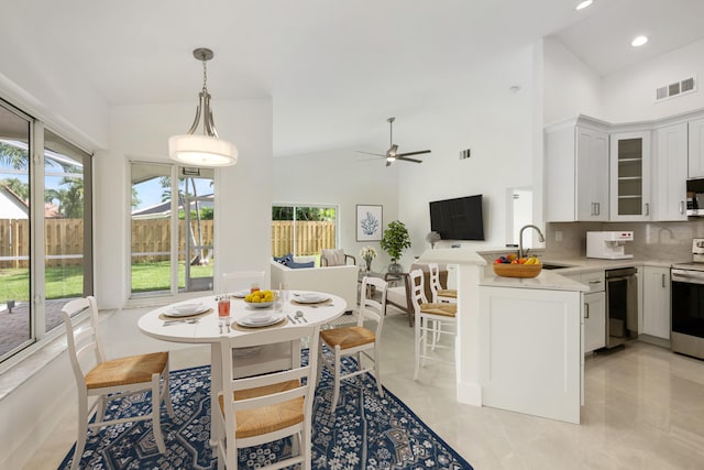 kitchen with kitchen peninsula, white cabinetry, sink, and high vaulted ceiling