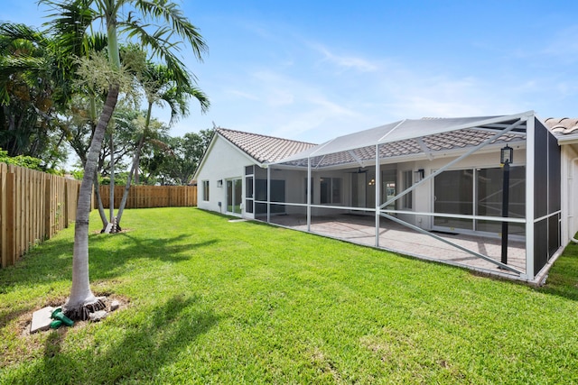 back of house with a yard, glass enclosure, and a patio area