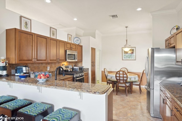 kitchen featuring a kitchen bar, kitchen peninsula, hanging light fixtures, and appliances with stainless steel finishes