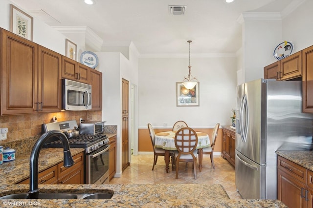 kitchen with backsplash, sink, dark stone countertops, appliances with stainless steel finishes, and decorative light fixtures