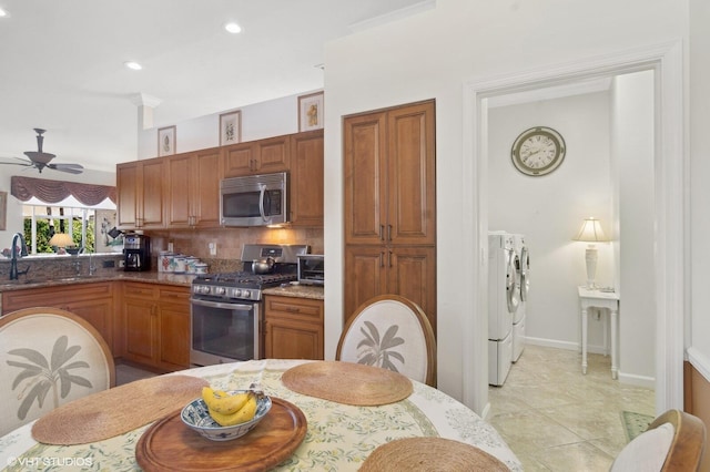 kitchen with backsplash, stainless steel appliances, ceiling fan, washer and clothes dryer, and sink