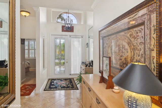 foyer featuring a notable chandelier, crown molding, and light tile patterned flooring