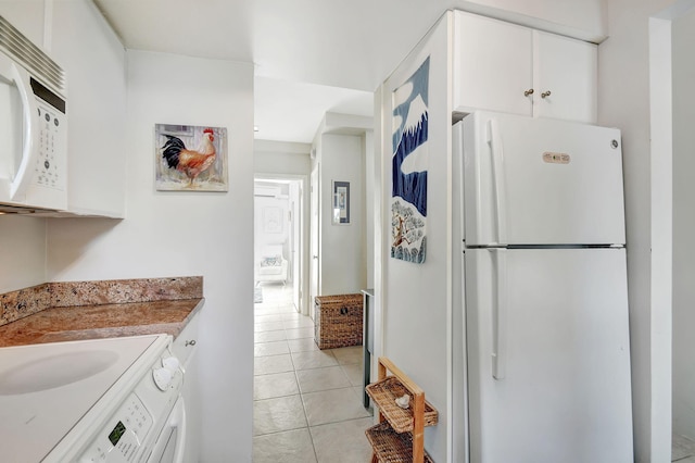 kitchen with white cabinets, washer / dryer, white appliances, and light tile patterned flooring