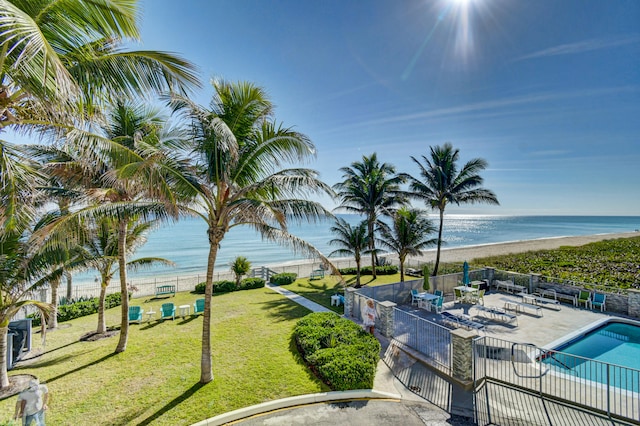 view of pool with a lawn, a water view, a patio, and a view of the beach