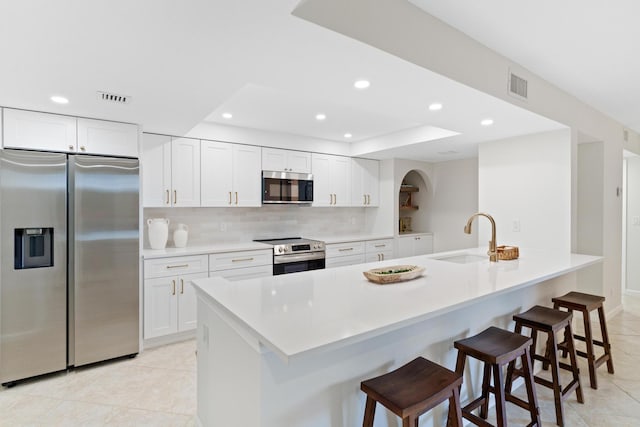 kitchen with a kitchen island with sink, stainless steel appliances, sink, and white cabinets