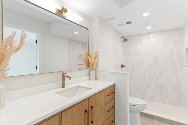 bathroom featuring tile patterned flooring, vanity, toilet, and tiled shower