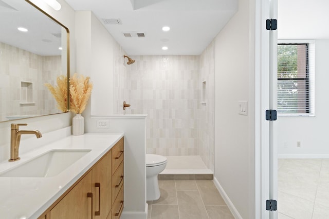 bathroom featuring tiled shower, vanity, tile patterned floors, and toilet