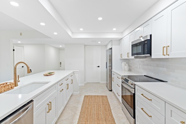 kitchen featuring stainless steel appliances, sink, light tile patterned flooring, backsplash, and white cabinetry