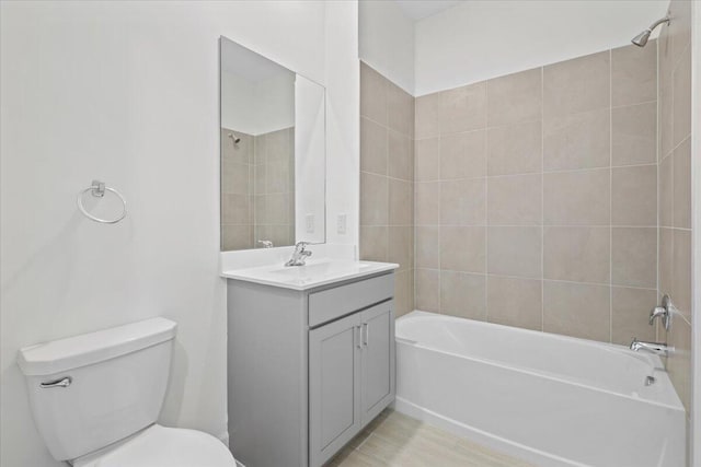 full bathroom featuring tiled shower / bath combo, toilet, and vanity