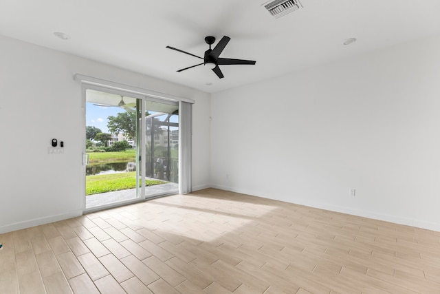 spare room with ceiling fan, light hardwood / wood-style floors, and a water view