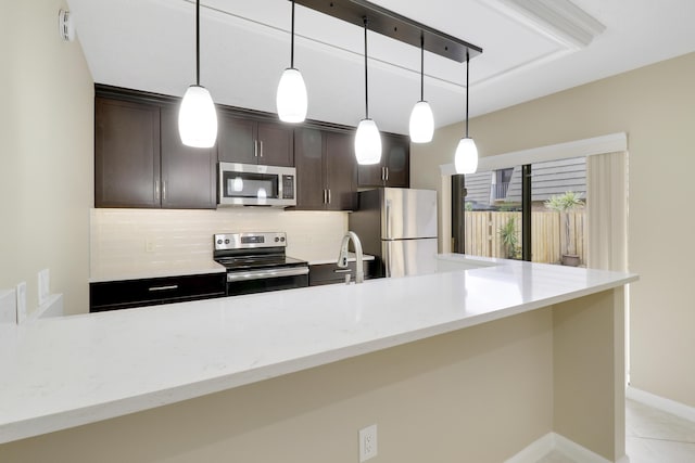 kitchen featuring stainless steel appliances, sink, light stone counters, decorative backsplash, and dark brown cabinetry