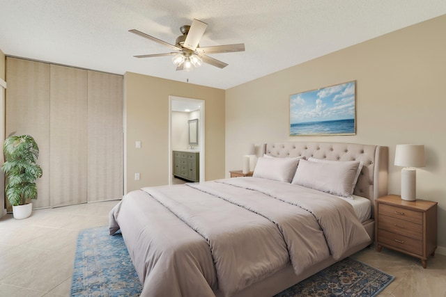 tiled bedroom with ceiling fan, ensuite bathroom, and a textured ceiling