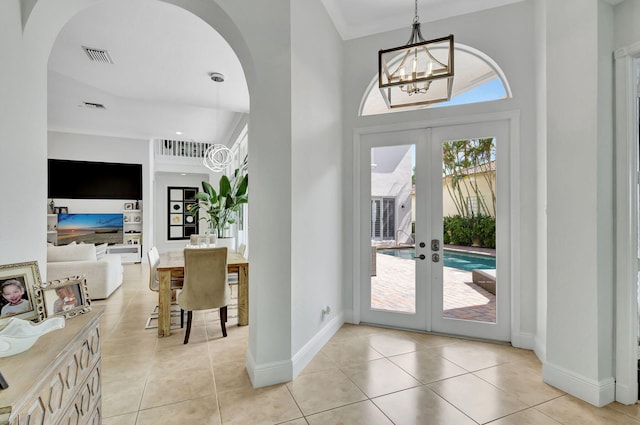 tiled entrance foyer featuring a towering ceiling, french doors, and an inviting chandelier