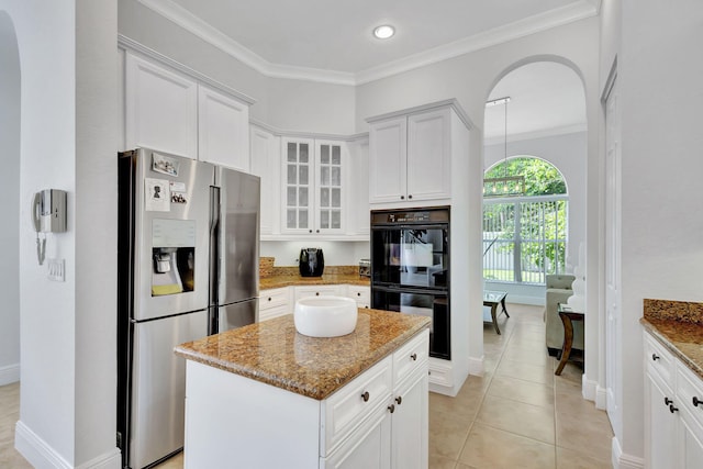 kitchen featuring a center island, stainless steel fridge with ice dispenser, black double oven, light stone countertops, and white cabinetry