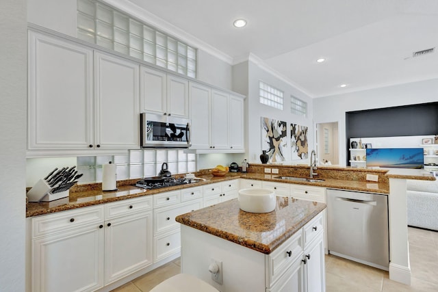 kitchen with white cabinets, appliances with stainless steel finishes, ornamental molding, and a center island