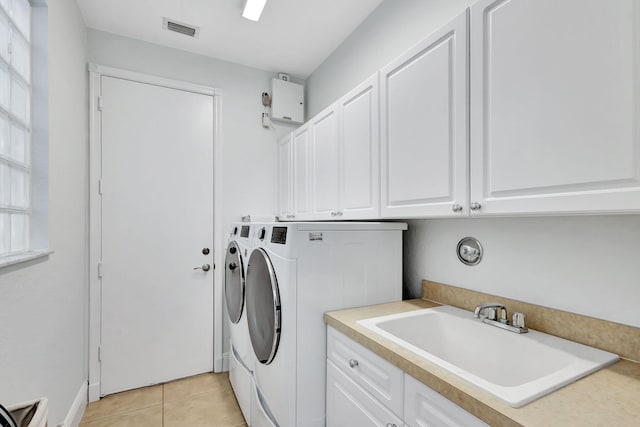 washroom with washing machine and clothes dryer, cabinets, light tile patterned floors, and sink