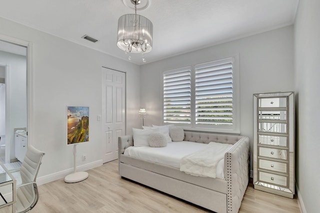 bedroom featuring light wood-type flooring and an inviting chandelier