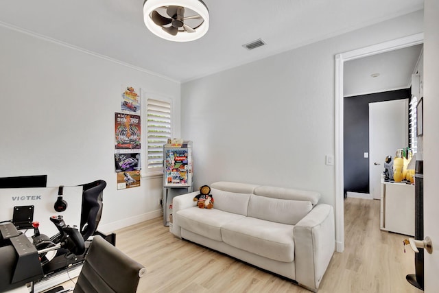 living room featuring ornamental molding, light wood-type flooring, and ceiling fan