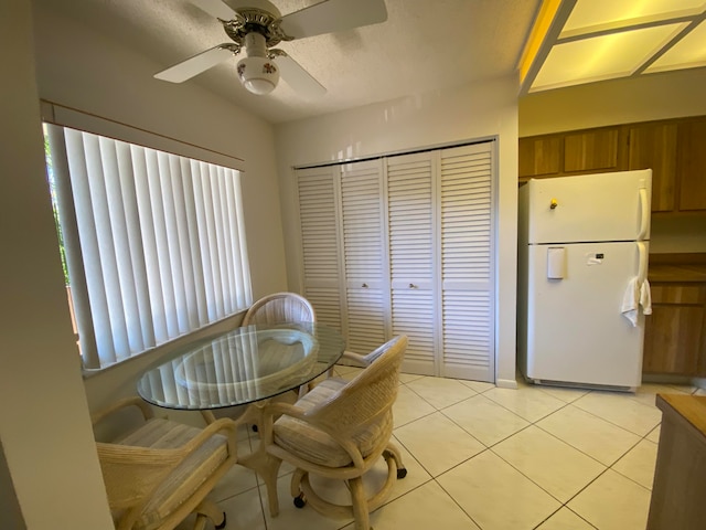 tiled dining room with ceiling fan and a textured ceiling