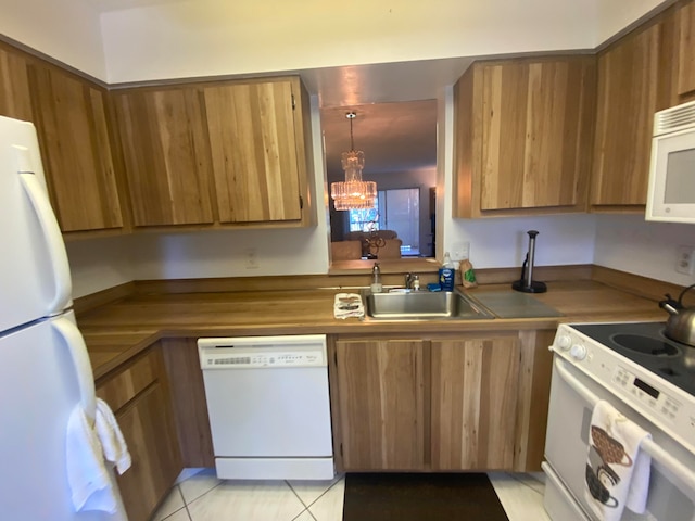 kitchen with white appliances, hanging light fixtures, sink, light tile patterned floors, and a notable chandelier