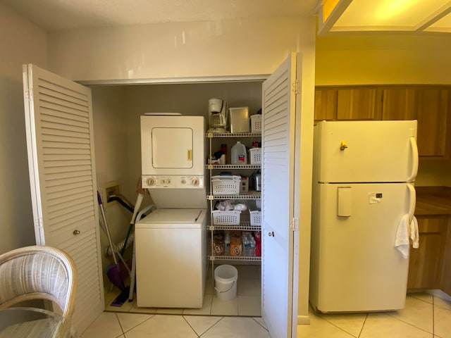 laundry room featuring stacked washing maching and dryer and light tile patterned floors