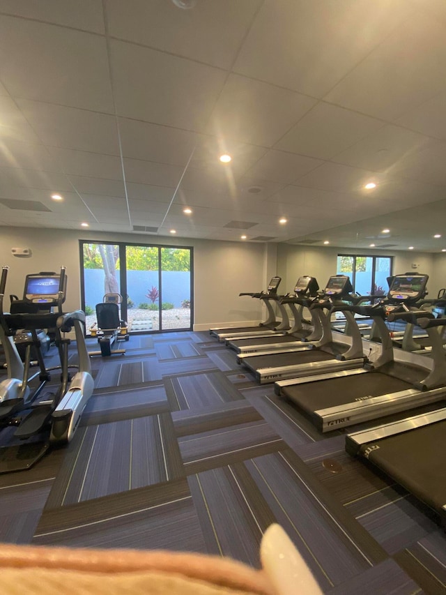 exercise room featuring dark colored carpet and a paneled ceiling