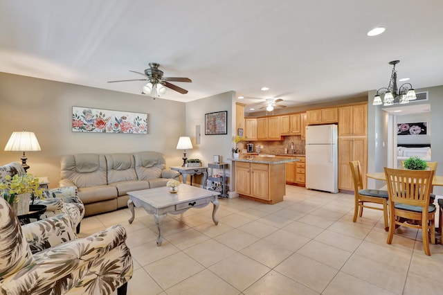 tiled living room with ceiling fan with notable chandelier