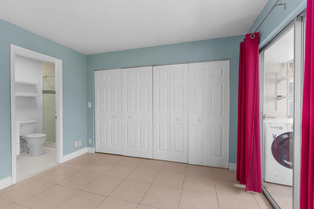 623 Monaco M, Delray Beach, FL 33446 - unfurnished bedroom with a closet, washer / dryer, ensuite bathroom, baseboards, and light tile patterned flooring