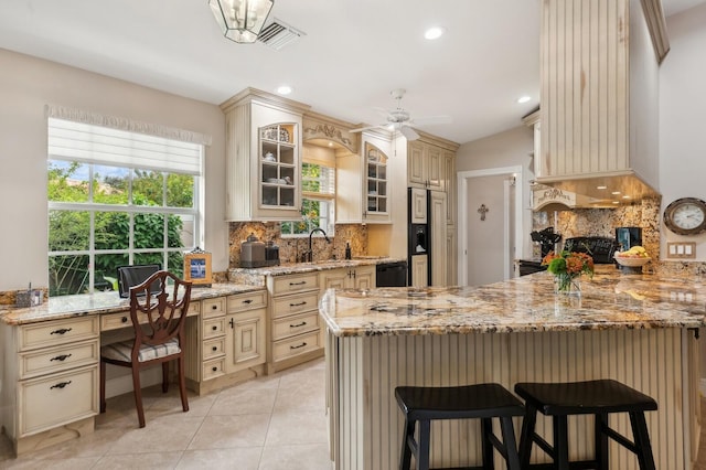 kitchen featuring a kitchen breakfast bar, sink, light stone counters, and cream cabinets