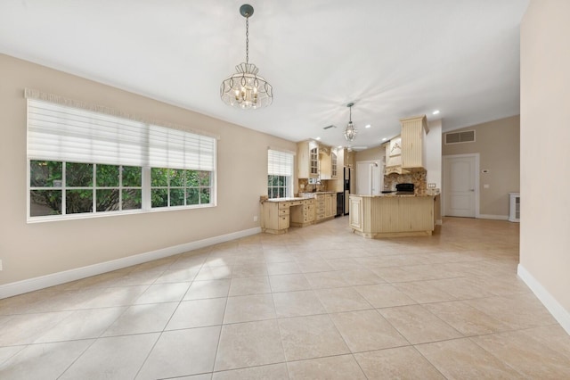 kitchen featuring hanging light fixtures, decorative backsplash, light tile patterned floors, light brown cabinetry, and a notable chandelier