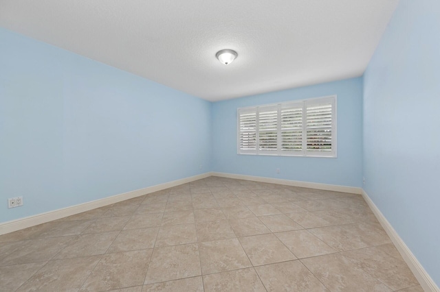 tiled spare room featuring a textured ceiling