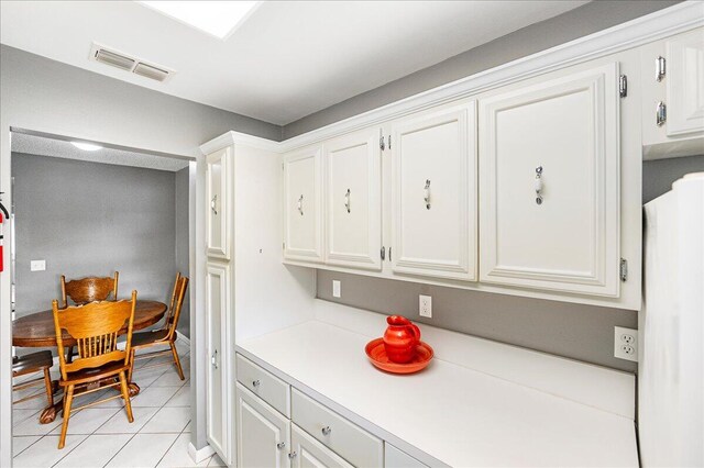 909 Savannas Point Dr Unit A, Fort Pierce, FL 34982 - kitchen with light tile patterned floors, white cabinets, light countertops, and freestanding refrigerator