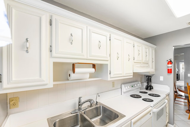 kitchen with light tile patterned floors, white appliances, white cabinetry, and sink