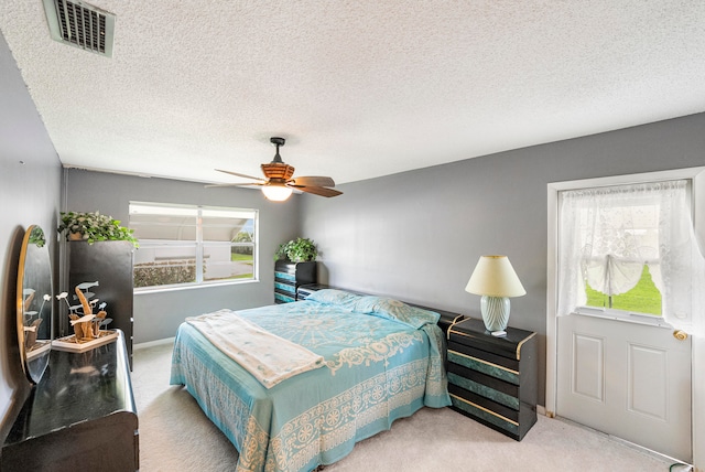 bedroom featuring a textured ceiling, light carpet, and ceiling fan