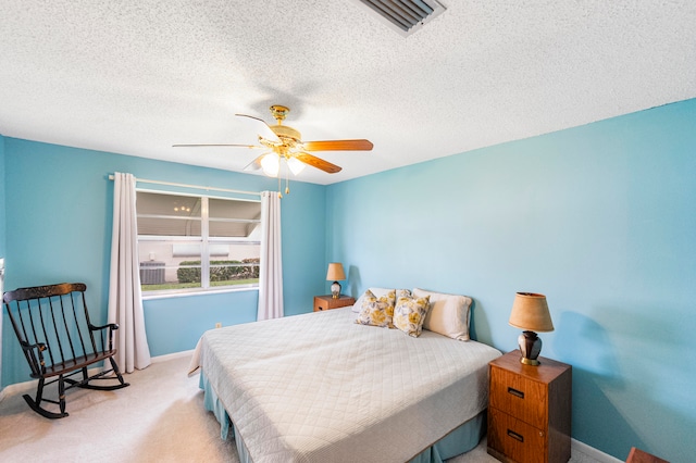 bedroom with a textured ceiling, light colored carpet, and ceiling fan