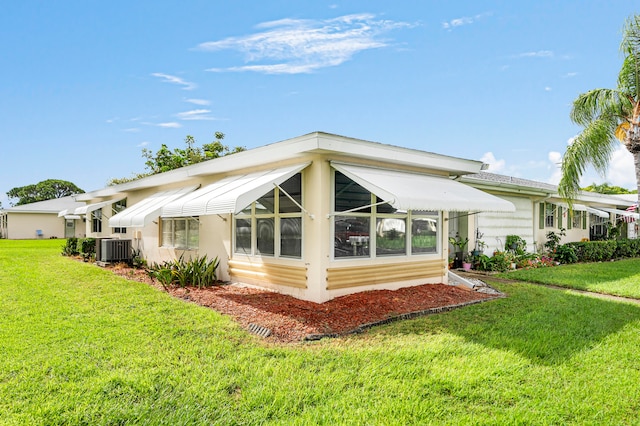 rear view of house with cooling unit and a lawn