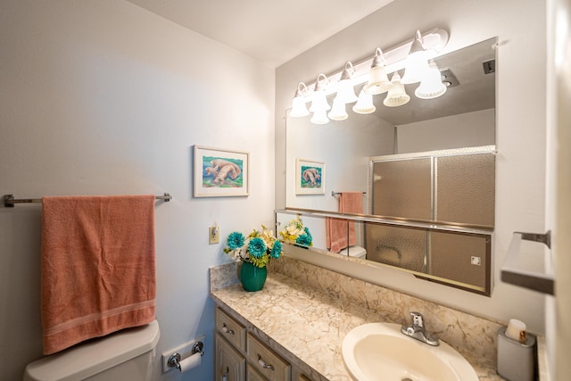 bathroom with vanity, toilet, and a shower with shower door