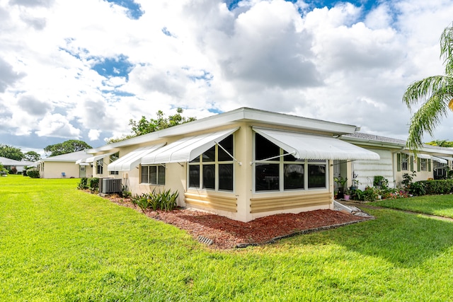 rear view of property with central air condition unit and a yard