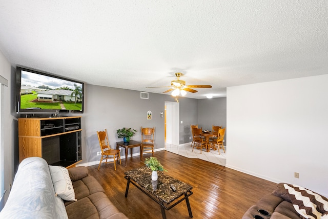 living room with a textured ceiling, hardwood / wood-style flooring, and ceiling fan