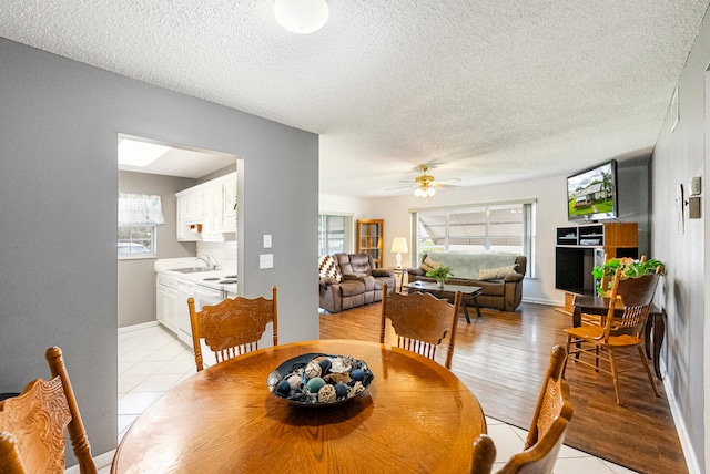 dining room featuring light wood-type flooring, plenty of natural light, a textured ceiling, and ceiling fan