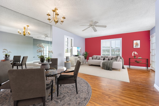 dining room with hardwood / wood-style flooring, ceiling fan with notable chandelier, and a textured ceiling