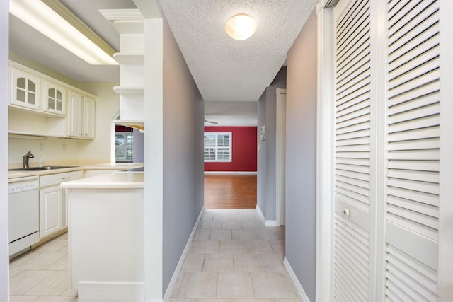 hall with light tile patterned floors, a textured ceiling, and sink