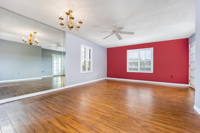 unfurnished room featuring hardwood / wood-style floors, plenty of natural light, a textured ceiling, and ceiling fan with notable chandelier