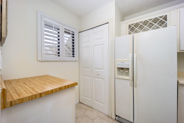 kitchen with white refrigerator with ice dispenser and a textured ceiling