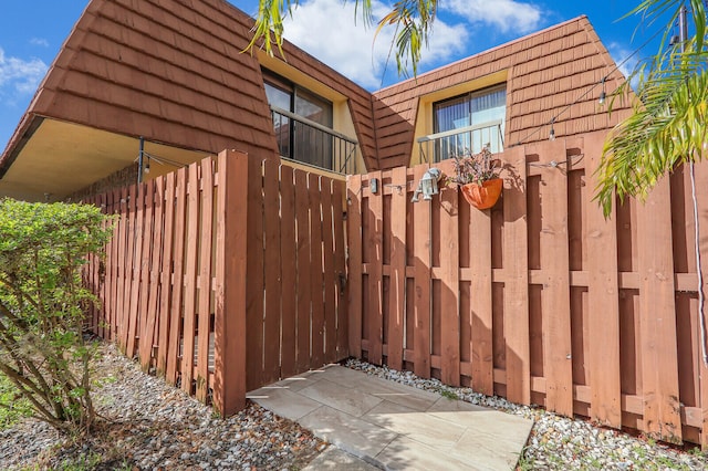 view of home's exterior featuring fence and mansard roof