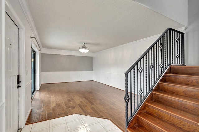 foyer entrance with a textured ceiling, hardwood / wood-style flooring, and crown molding