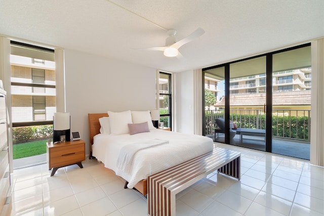 tiled bedroom featuring ceiling fan, access to exterior, a textured ceiling, and floor to ceiling windows