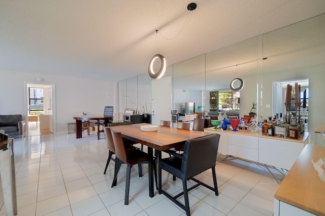 dining room with a healthy amount of sunlight, light tile patterned floors, and a textured ceiling