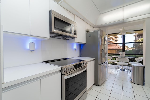 kitchen with white cabinets, stainless steel appliances, light tile patterned floors, and tasteful backsplash