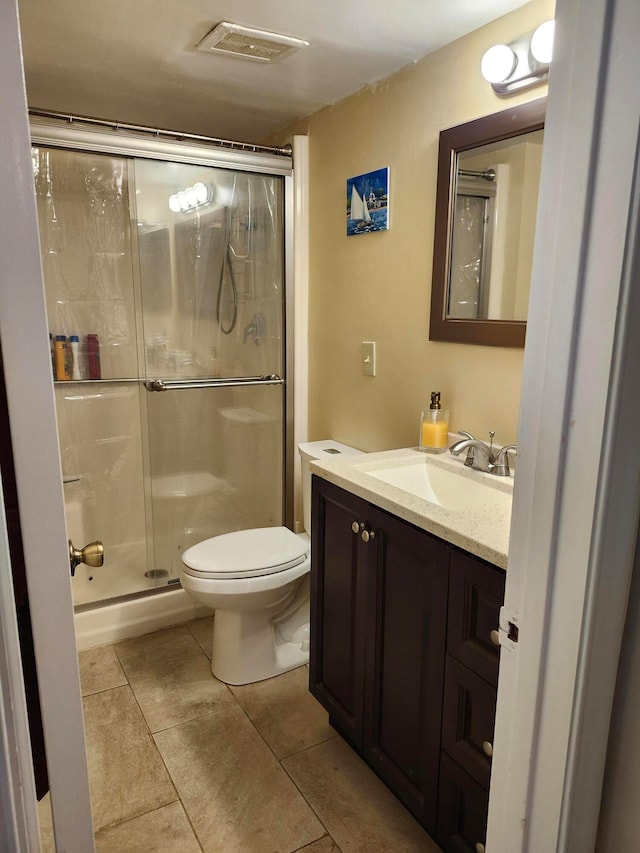 bathroom featuring tile patterned flooring, vanity, an enclosed shower, and toilet